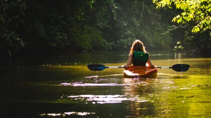 girl kayaking alone on river